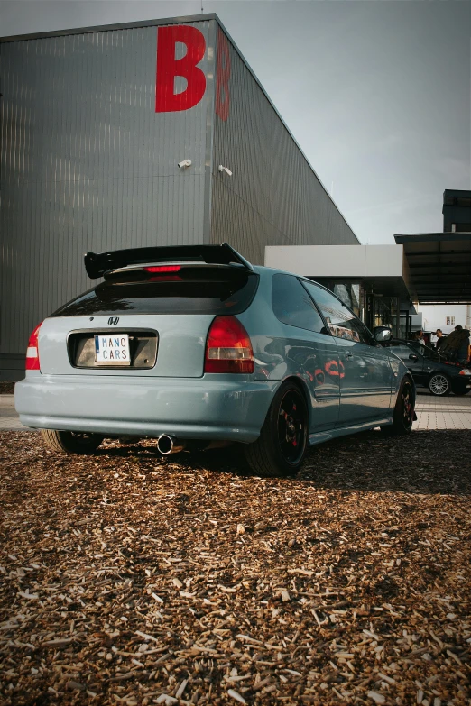 the back end of a grey car parked in front of a building