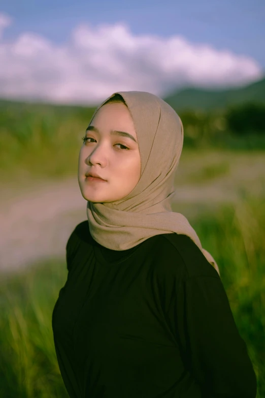 a woman stands in grass and looks into the distance