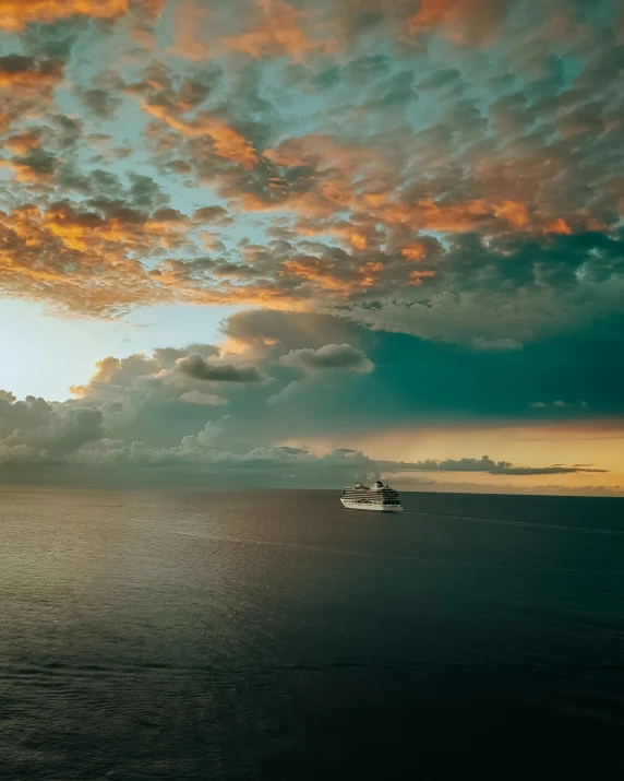 a boat on the ocean under a colorful cloud sky