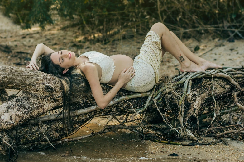 pregnant woman laying on the ground in natural environment