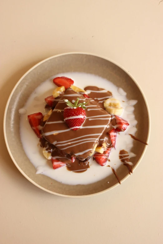 there is a small plate with strawberrys and chocolate dessert