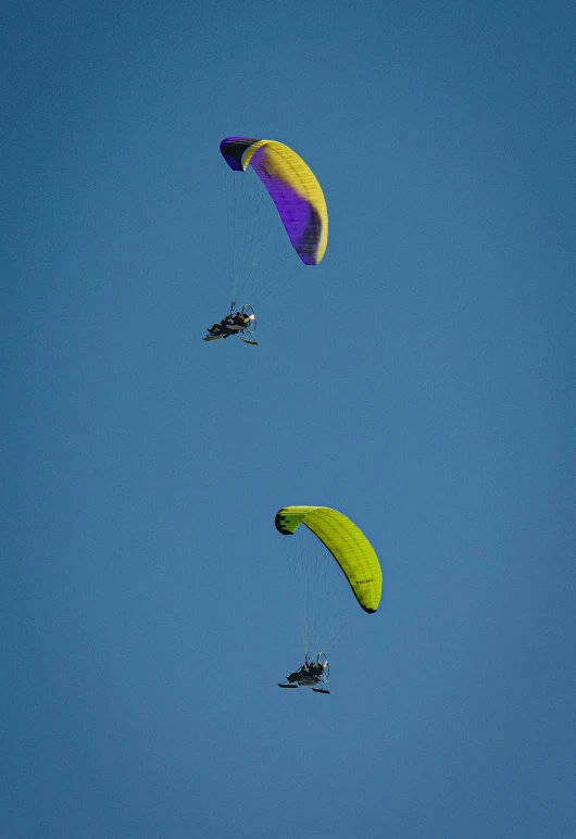 two parachutes and one plane in a blue sky