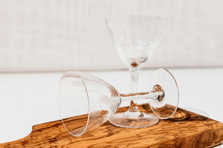 a wine glass and some other glasses sit on a  board