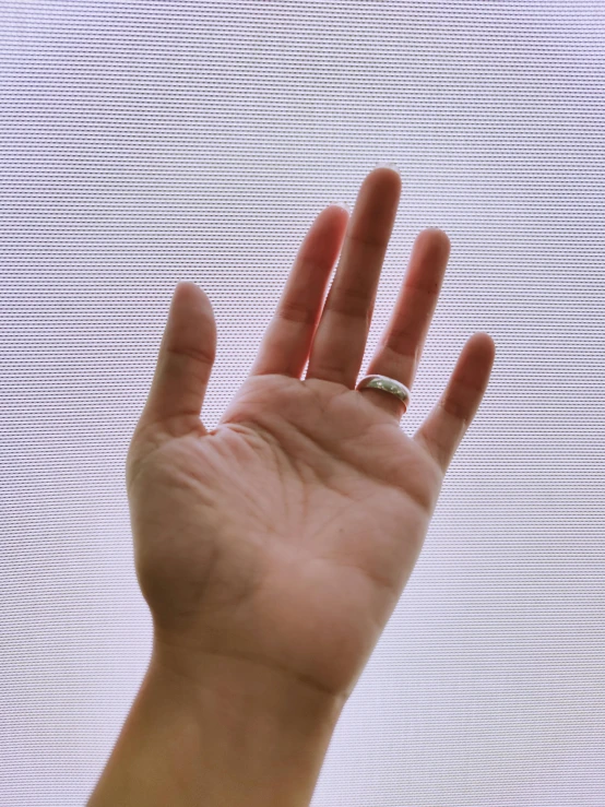 a person's hand is in the air with the light from the window