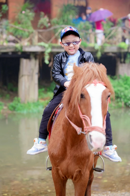 a little boy riding a horse in the water