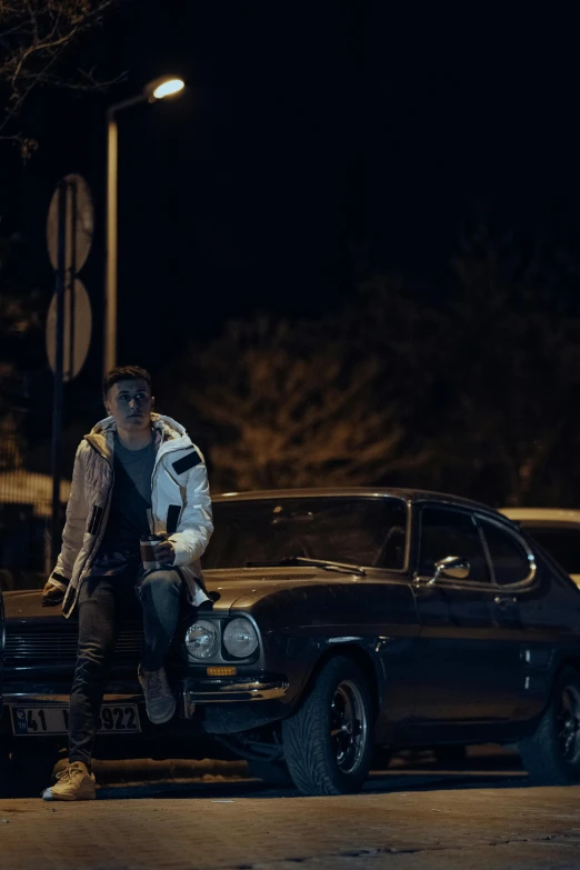 a man sitting on the hood of a black car