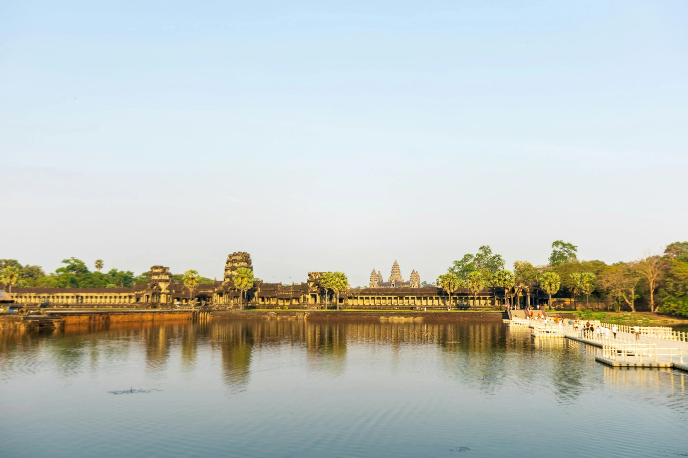 a pond surrounded by lush vegetation with many structures in the distance