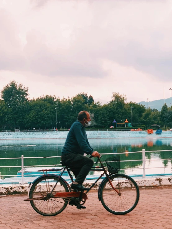 an older man is riding his bike near the lake