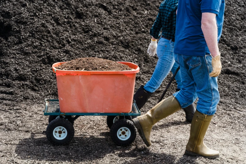 someone with boots hing a wheel barrow in the dirt