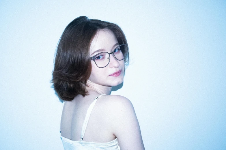 a girl in glasses and white dress in a white room