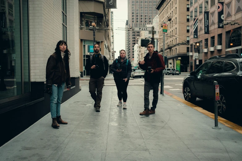 four people are walking along the city street