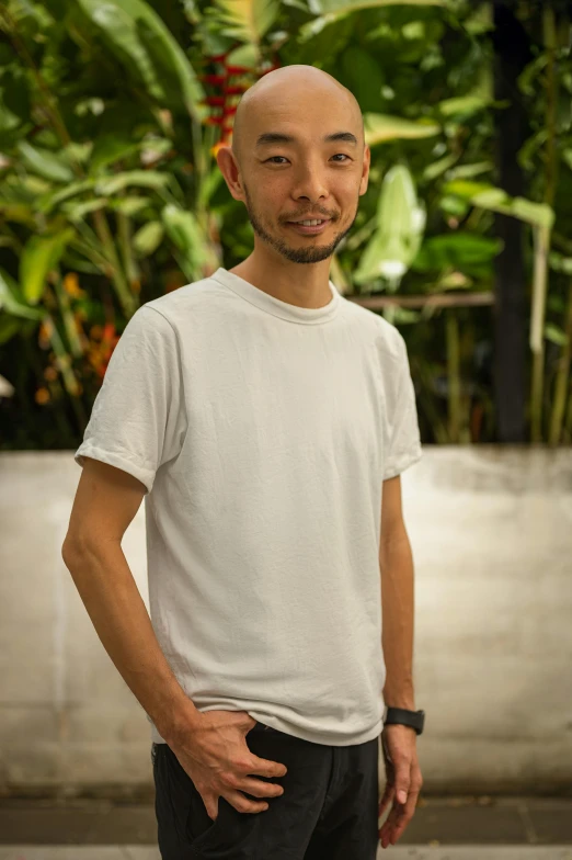 a bald man in a white tee shirt poses for a picture