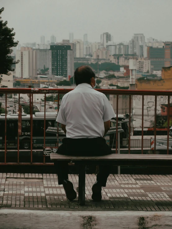 the man in white is sitting on a bench outside