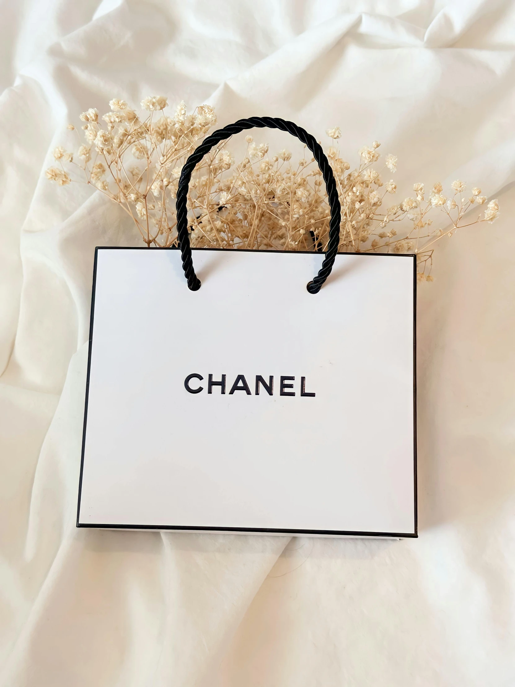 a white paper bag with the words chanel on it