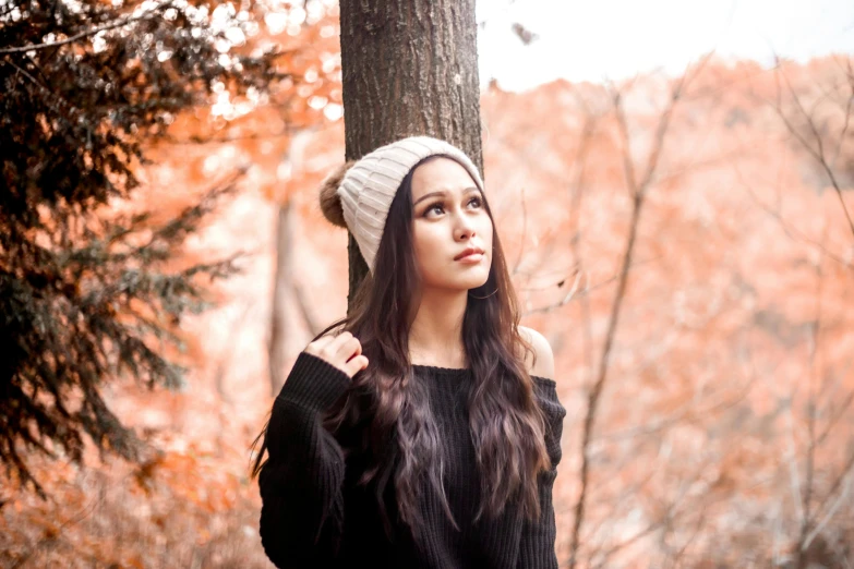 a woman in black shirt standing next to a tree