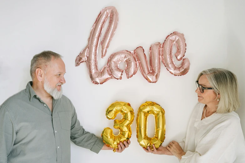 a man and a woman holding balloons reading the word 80