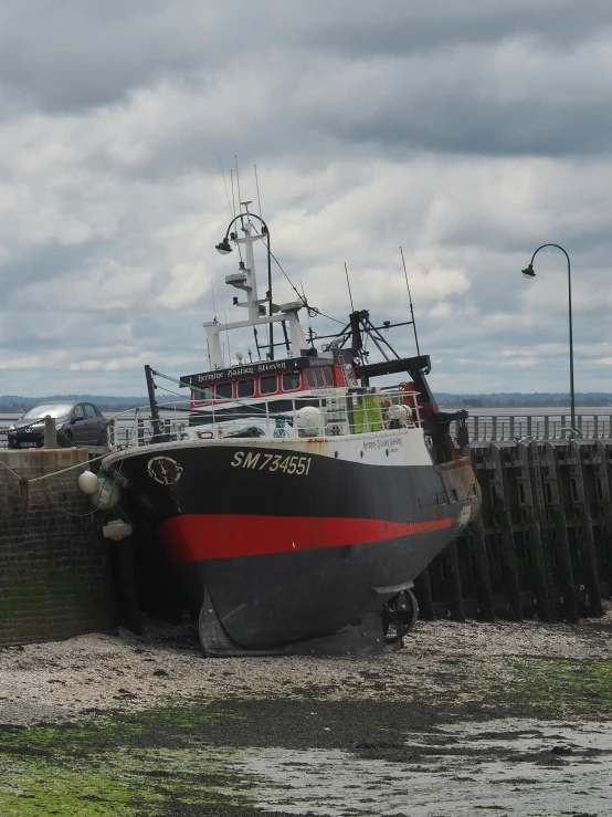 a large black and red boat on the side of the beach