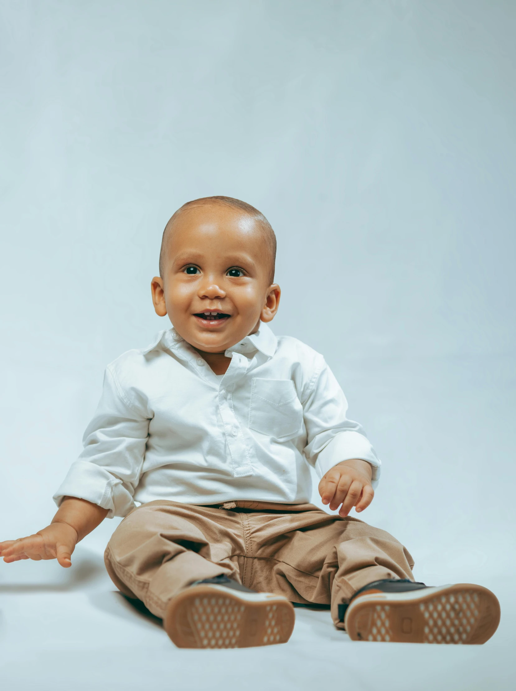 a baby sitting on the floor with his hand extended