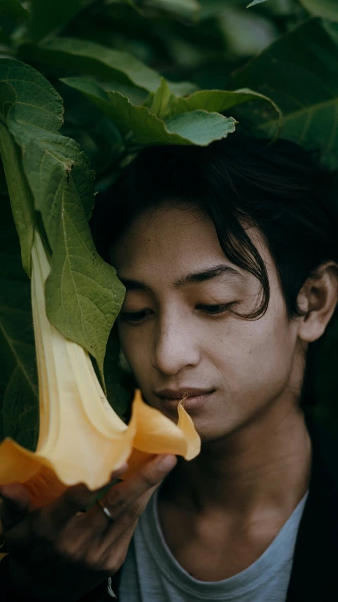 man is smelling a flower in a forest