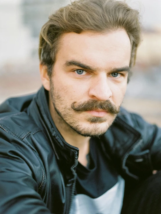 a man with a goatee in black jacket posing for a po