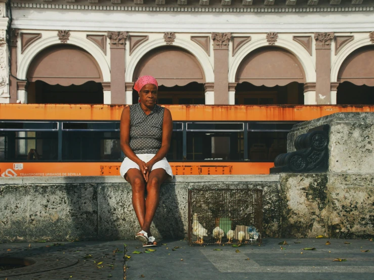 a woman sitting on a cement wall next to a bus