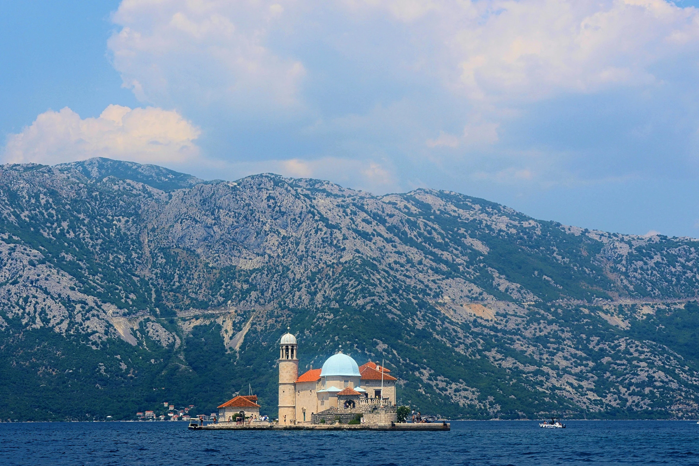 a building sits in the water with mountains in the background