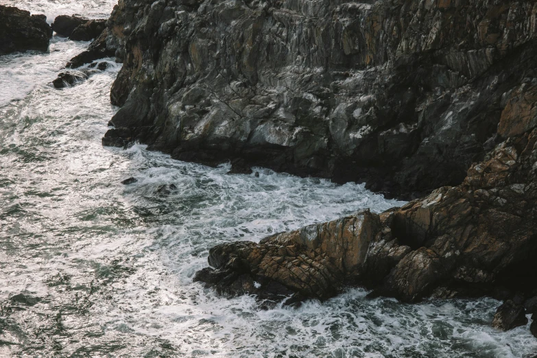 a cliff with very rough rocky water between two large rocks