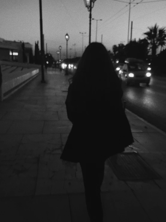 a woman is walking down the street in front of some cars