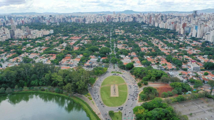 an aerial view of a city with lots of trees, grass and water