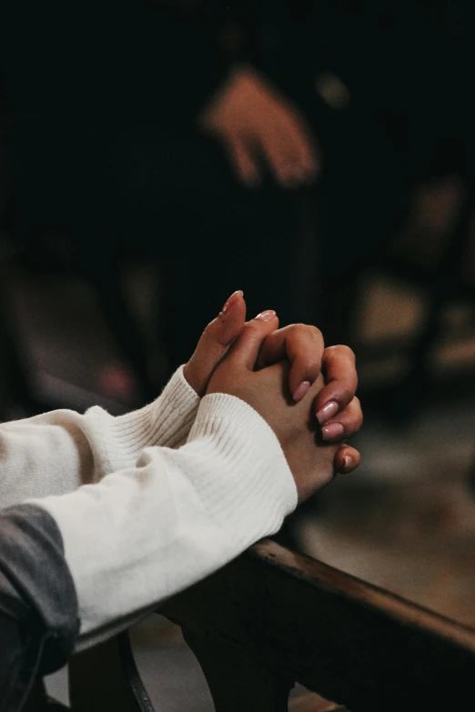 two hands clasp together on a bench in front of some people