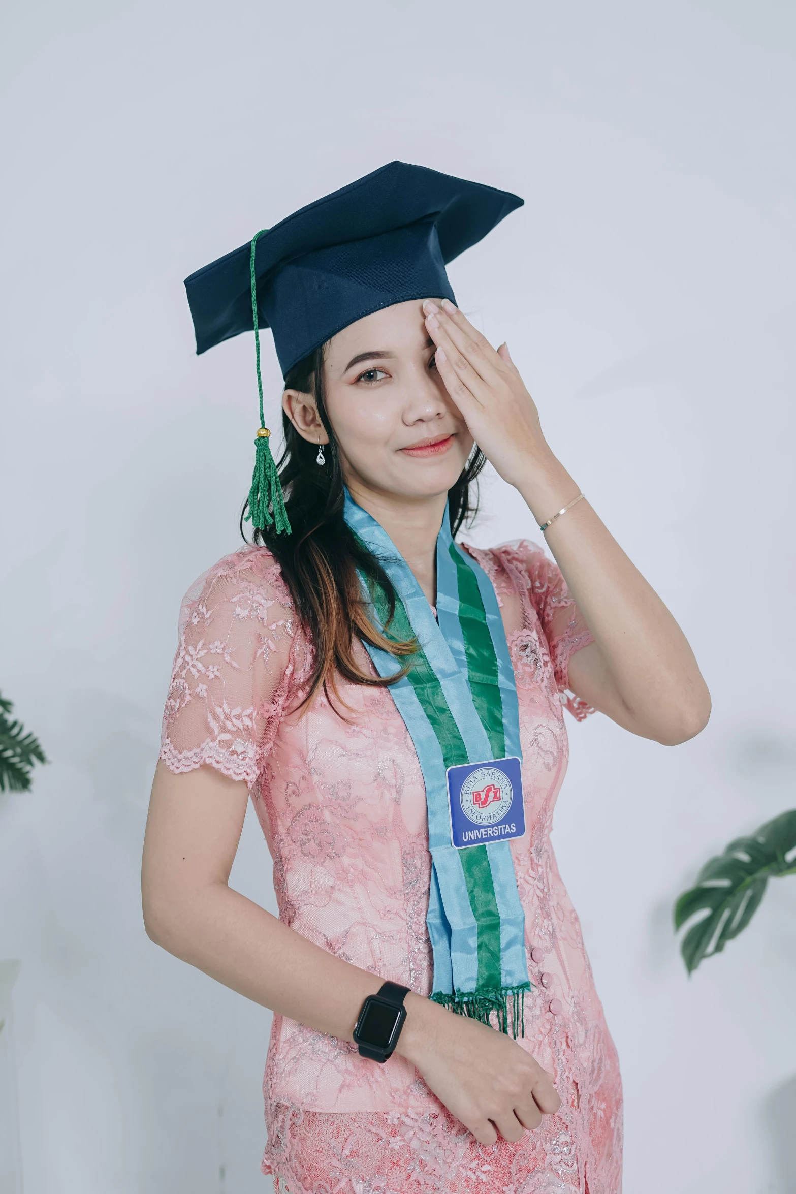 a woman wearing a graduation hat and holding her hand to her forehead