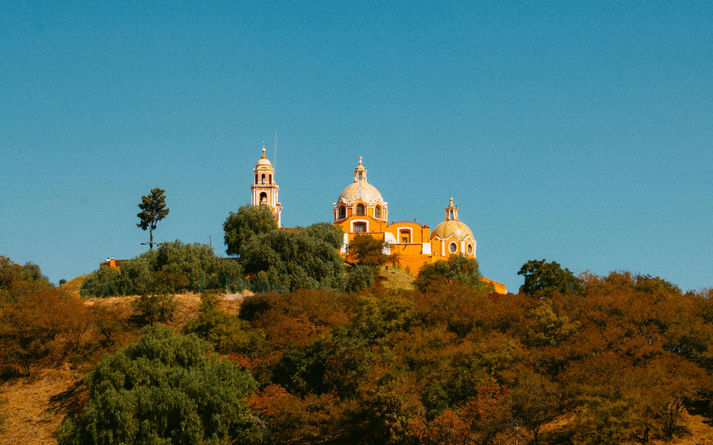 a large church on top of a hill with trees in front of it