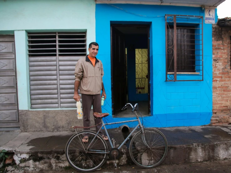 man standing next to a parked bicycle near a doorway