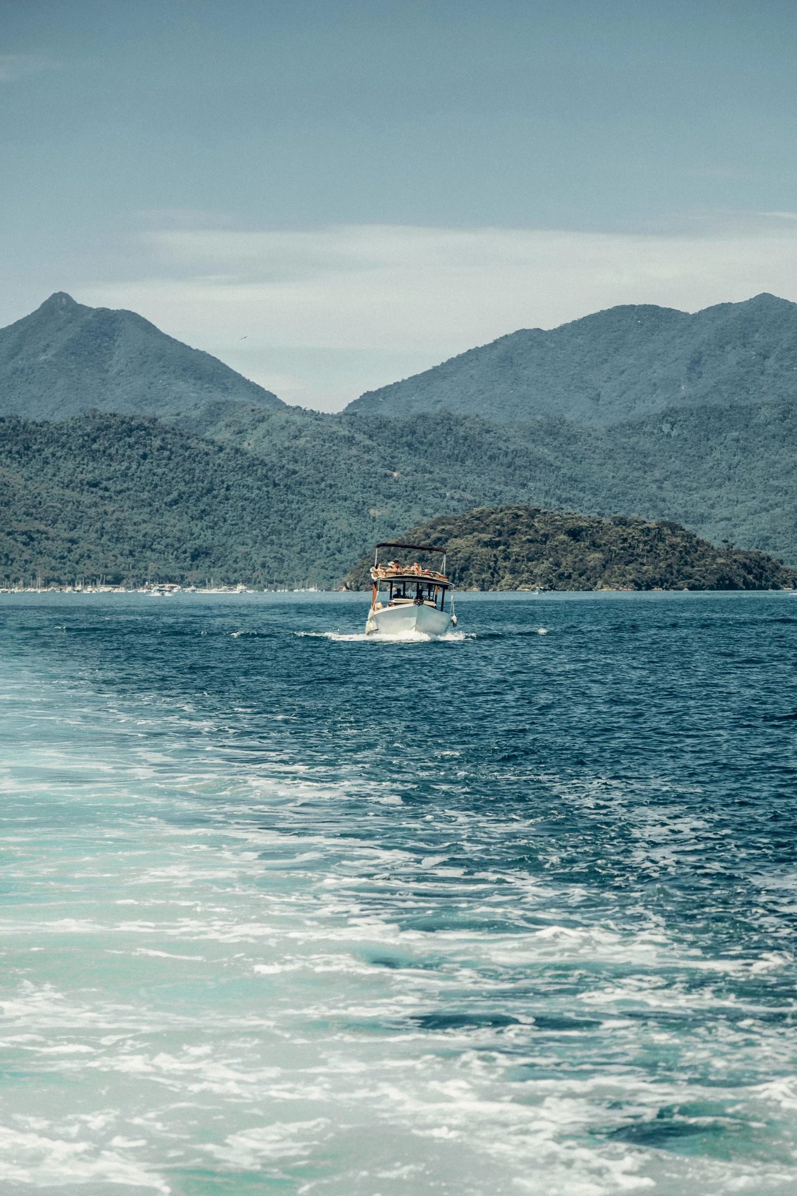 a boat sailing near some mountains on a body of water