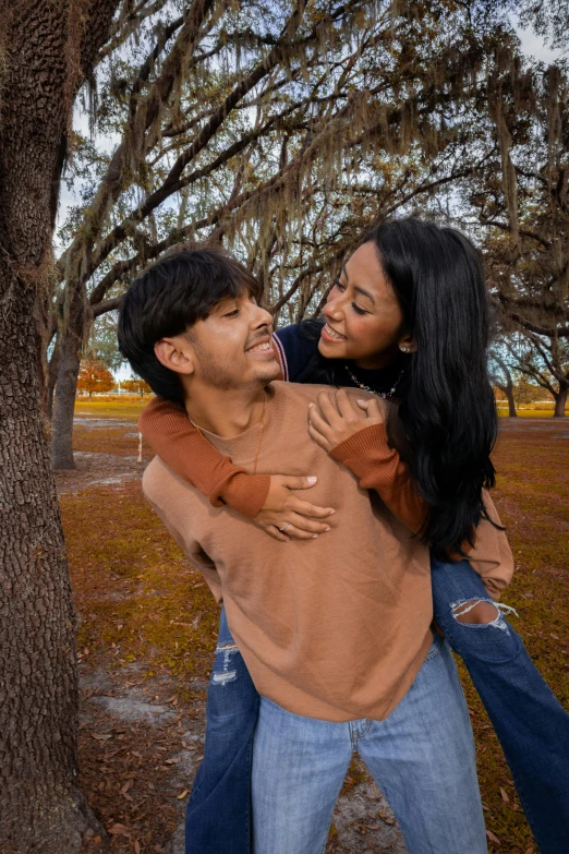 a man giving a woman a hug while standing near trees