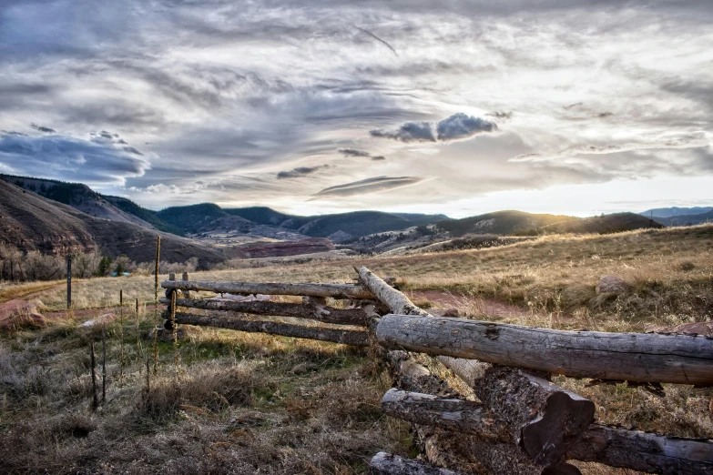 a rustic country scene with a wooden fence and mountain scenery