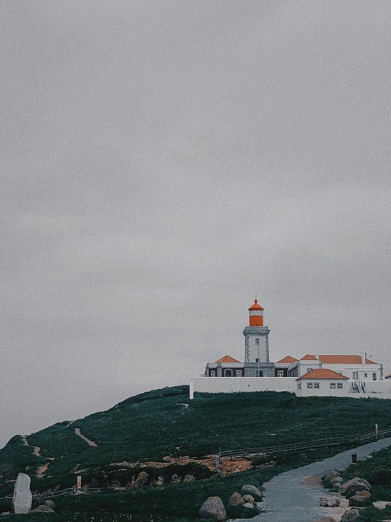 lighthouse on a hill with rocks in the foreground