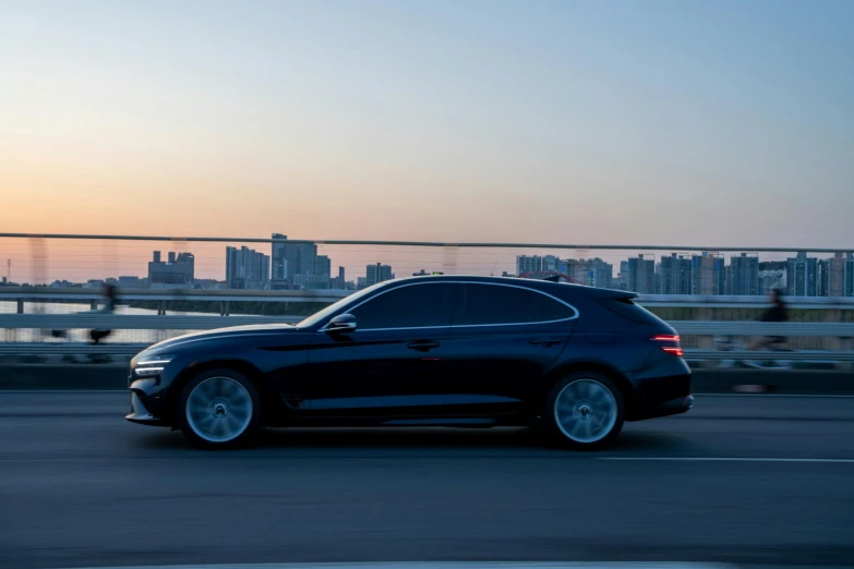 black car driving on street near bridge with city in the background