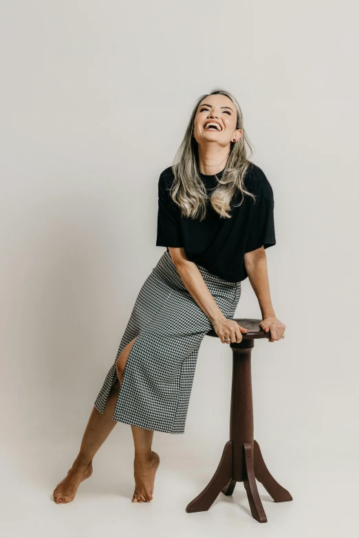 woman posing on a stool, laughing