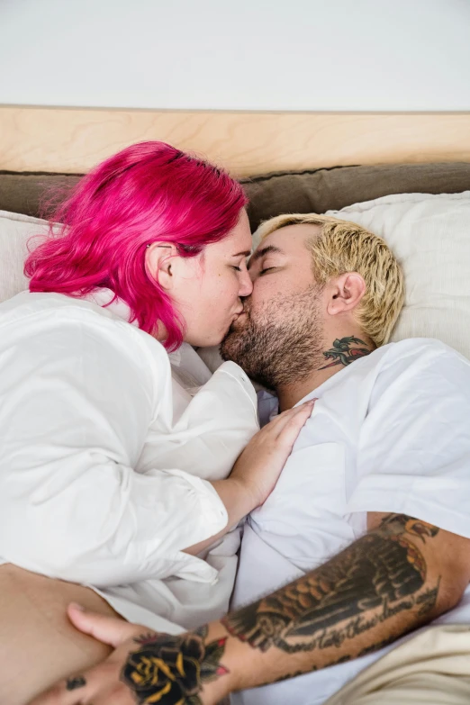 two people in bed with pink hair kissing each other