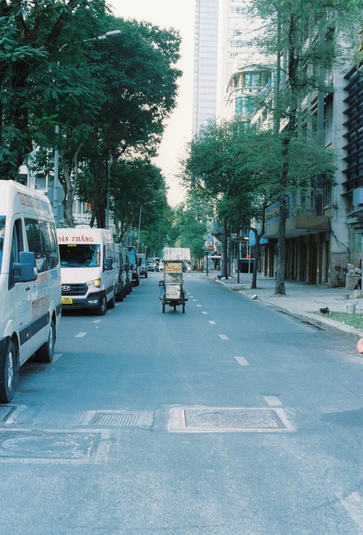 an image of a small city street scene with a bike rider riding in the middle