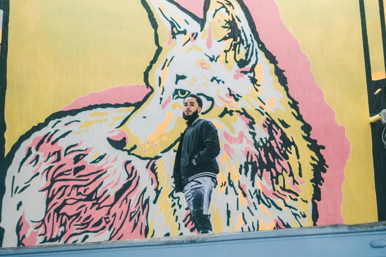 a man standing in front of a picture of a wolf on a building