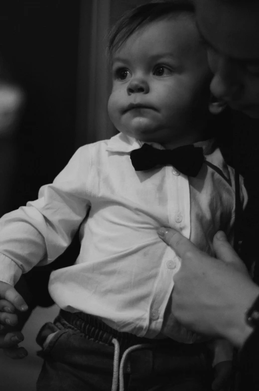 a man holding a young child with a bow tie