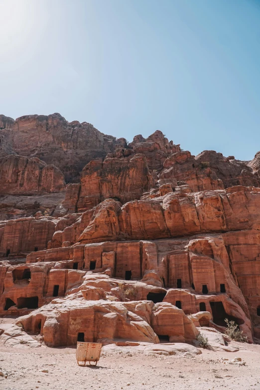 a chair sitting on a beach in front of large rock formations