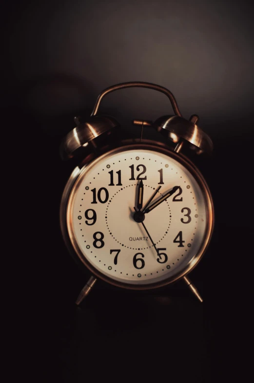 an alarm clock with bells on a dark surface