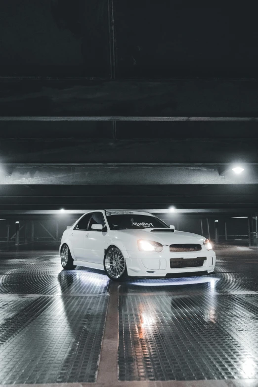 the white car in a parking garage at night