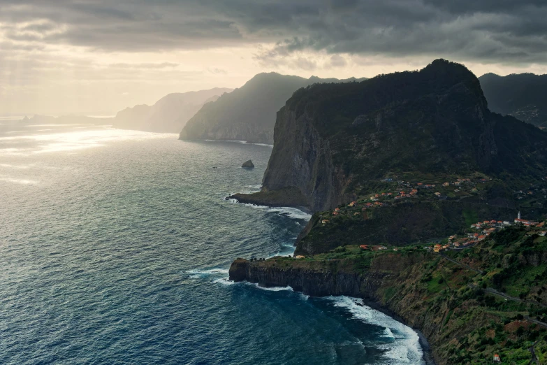 a large rock formation over the ocean with a small village on top