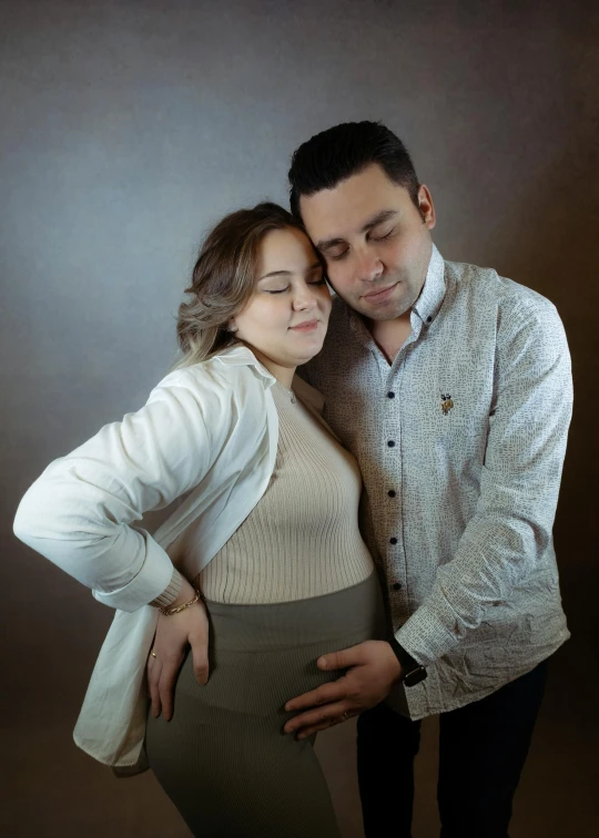 a pregnant couple pose for a po while holding each other