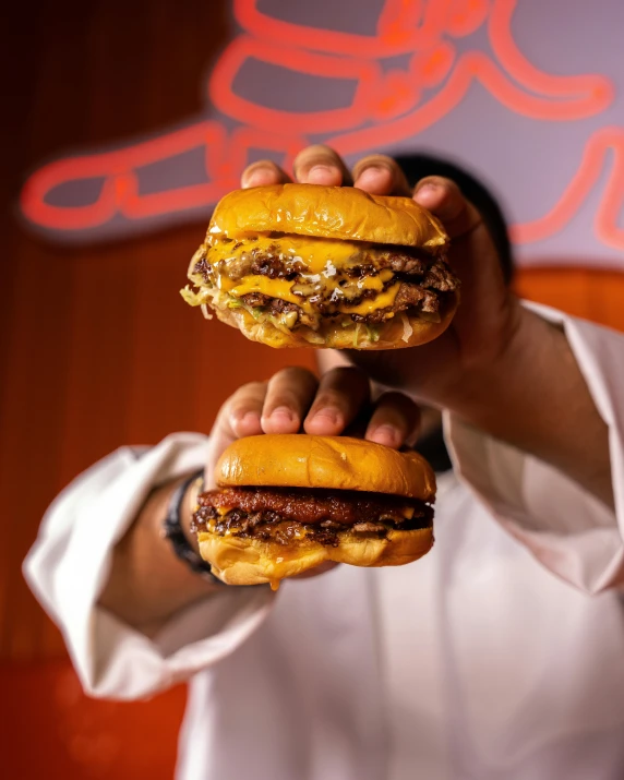 a man holding two hamburgers with toppings