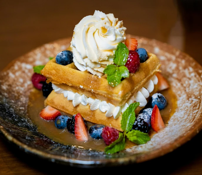 a pile of waffles with some whipped cream on top of them